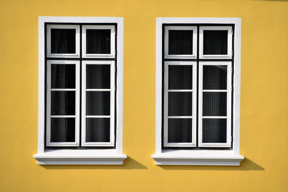 Two white-framed windows on a vibrant yellow building facade in Büsum, Germany.